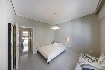 a white bedroom with a bed and a lamp at Central Halandri apartment near all hospitals in Athens