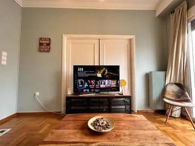 a living room with a tv and a wooden floor at ATHENS Penthous at Center in Athens