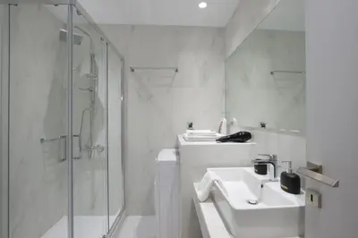 a white bathroom with a sink and a shower at Victoria Sq., A cozy and stylish apartment in Athens