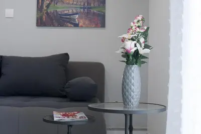 a vase of flowers sitting on a table next to a couch at Victoria Sq., A cozy and stylish apartment in Athens