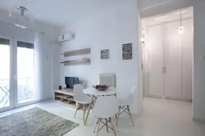 a white living room with a table and chairs at Victoria Sq., A cozy and stylish apartment in Athens
