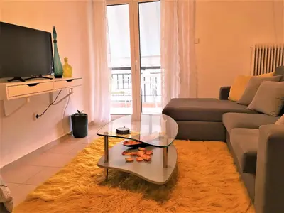 a living room with a couch and a glass coffee table at Cozy Studio by seaside and tram in Athens