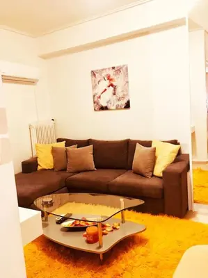 a living room with a brown couch and a glass table at Cozy Studio by seaside and tram in Athens