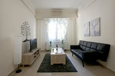 a living room with a couch and a tv at Comfortable apartment at the foot of the Odeon of Herodes Atticus in Athens
