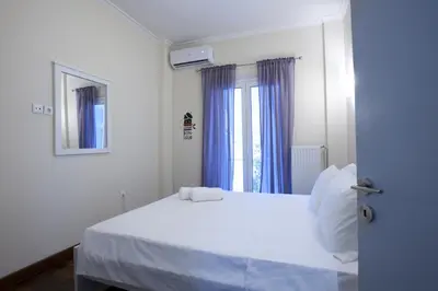 a bedroom with a white bed with blue curtains at Comfortable apartment at the foot of the Odeon of Herodes Atticus in Athens