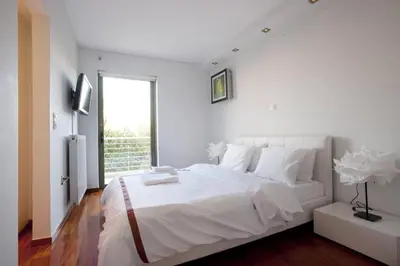 a white bedroom with a large bed and a window at Voula, A modern, minimal and stylish, apartment in Athens