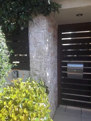 a stone wall with black blinds on a window at Voula, A modern, minimal and stylish, apartment in Athens