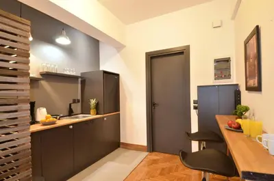 a kitchen with black cabinets and a wooden table at A modern rustic cosy apartment at the foot of Mount Lycabettus in Athens