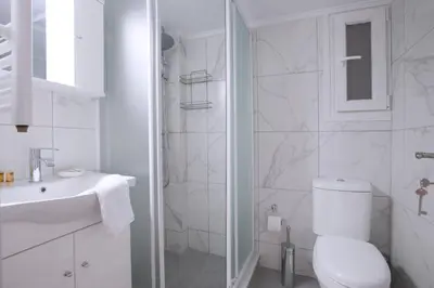 a white bathroom with a toilet and a sink at Pop art apartment at Koukaki in Athens