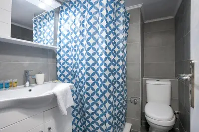 a bathroom with a blue and white shower curtain and a toilet at Pop art apartment at Koukaki in Athens