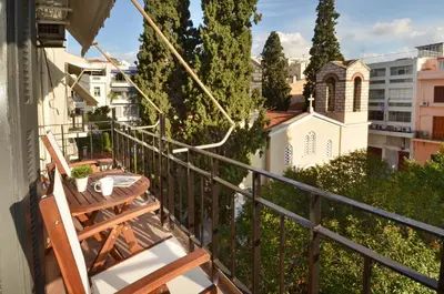 a balcony with a table and chairs and a church at Plaka, Apartment in the old historical neighborhood of Athens in Athens