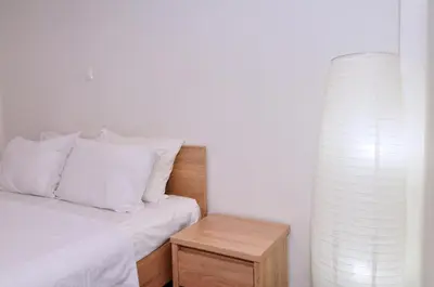 a bed with white pillows and a wooden night stand at Koukaki, a minimal studio in Athens