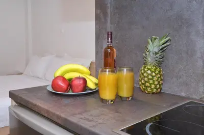 a table with a plate of fruit and two glasses of juice at Koukaki, a minimal studio in Athens