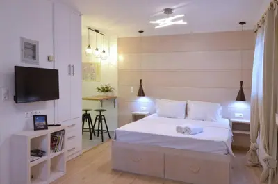 a bedroom with a white bed and a television at Petralona, a sweet and cozy apartment in Athens