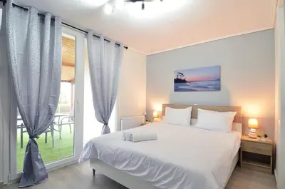 a bedroom with a white bed and a large window at Agia Paraskevi, a cozy and minimal retire in Athens