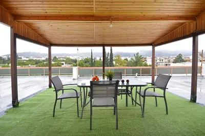 a patio with a table and chairs on a tennis court at Agia Paraskevi, a cozy and minimal retire in Athens