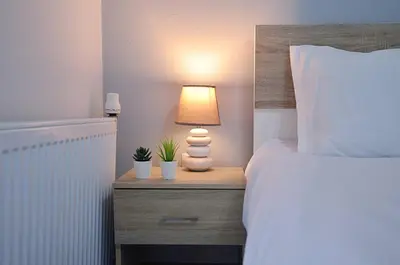 a bedroom with a bed and a lamp on a night stand at Agia Paraskevi, a cozy and minimal retire in Athens