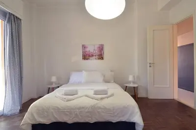 a bedroom with a large white bed with a light fixture at Kerameikos, a lovely apartment in Athens