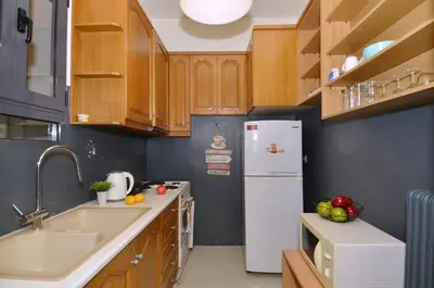 a kitchen with wooden cabinets and a white refrigerator at Kerameikos, a lovely apartment in Athens