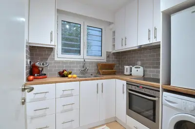 a white kitchen with white cabinets and a window at Acropolis, a nice and minimal apartment in Athens