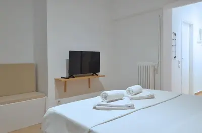 a white room with a bed with towels and a tv at Acropolis, a nice and minimal apartment in Athens