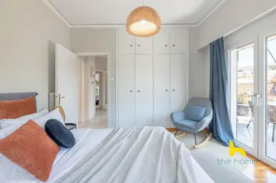 a bedroom with a bed and a blue chair at Sun-splashed sanctum with big balconies, Acropolis 2 in Athens