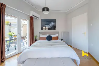 a man is sitting on a bed in a bedroom at Sun-splashed sanctum with big balconies, Acropolis 2 in Athens