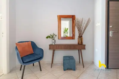 a room with a table and a blue chair and a mirror at Sun-splashed sanctum with big balconies, Acropolis 2 in Athens