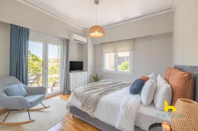 a bedroom with a bed and a chair and a window at Sun-splashed sanctum with big balconies, Acropolis 2 in Athens