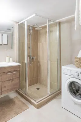 a bathroom with a shower and a washing machine at Explore History from a Chic Central Apartment in Athens