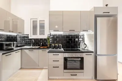 a kitchen with white cabinets and a stainless steel refrigerator at Stylish, 3-brdm Family Apartment near Acropolis! in Athens