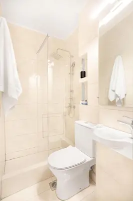 a white bathroom with a toilet and a shower at Stylish, 3-brdm Family Apartment near Acropolis! in Athens