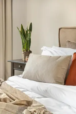 a bed with white sheets and pillows and a plant at Stylish, 3-brdm Family Apartment near Acropolis! in Athens