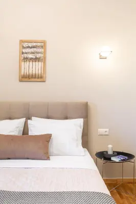 a bedroom with a bed with white pillows and a table at Deluxe 3-BDRM Urban-industrial Apt at Acropolis in Athens