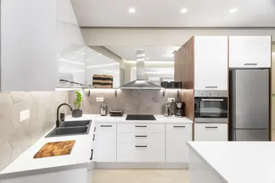 a kitchen with white cabinets and a stainless steel refrigerator at Deluxe 3-BDRM Urban-industrial Apt at Acropolis in Athens