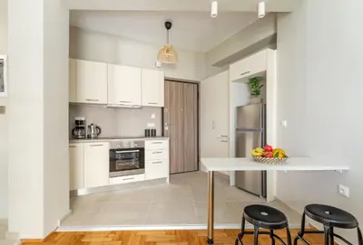 a kitchen with white cabinets and a table and chairs at Discover Athens from Urban Hideaway, Acropolis View in Athens