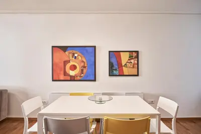 a dining room with a white table and three paintings at Contemporary & Comfy Apt next to Acropolis Museum in Athens