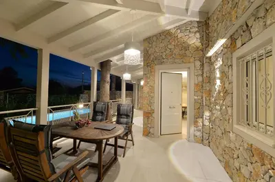 a dining room with a table and chairs on a balcony at Lagonisi luxurious residence Ruby's Pool Villa in Lagonissi