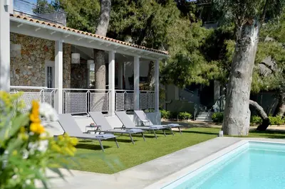 a group of white lounge chairs next to a pool at Lagonisi luxurious residence Ruby's Pool Villa in Lagonissi