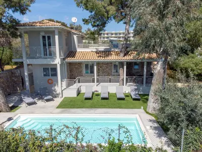 a house with a swimming pool in front of a house at Lagonisi luxurious residence Ruby's Pool Villa in Lagonissi