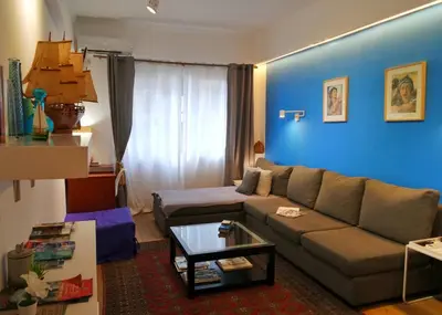 a living room with a couch and a blue wall at Royal Blue Grand Suite No 3 in Piraeus