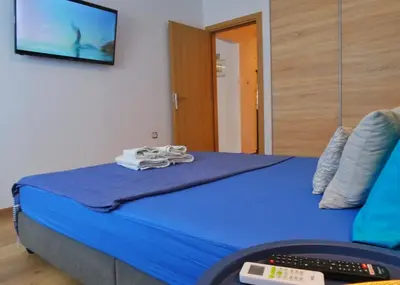 a bedroom with a blue bed with a television on the wall at Royal Blue Grand Suite No 3 in Piraeus