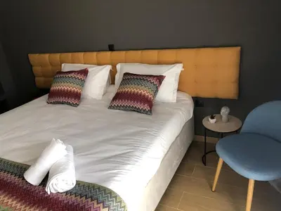 a bedroom with a bed with two pillows and a chair at Metropolitan Complex Suite Faliro in Piraeus