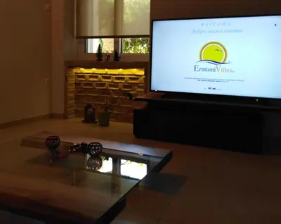 a living room with a tv and a glass table at Piraeus Suite~Ermioni Villas in Piraeus