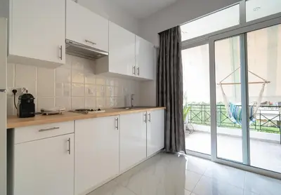 a kitchen with white cabinets and a large window at Cinema Zeus Studios - by Avelink in Spáta