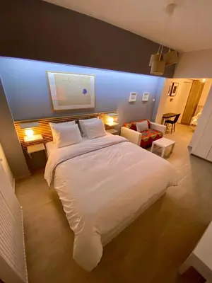 a bedroom with a large white bed and a living room at For a genuine Athenian homestay! in Athens