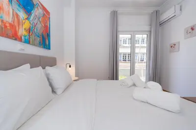 a white bedroom with a large bed with white pillows at Melodies of Athens apt in Ilisia neighbourhood in Athens