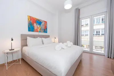 a white bedroom with a large white bed and a window at Melodies of Athens apt in Ilisia neighbourhood in Athens