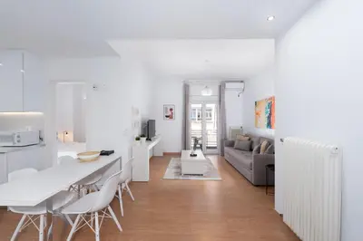 a white kitchen and living room with a table and chairs at Melodies of Athens apt in Ilisia neighbourhood in Athens