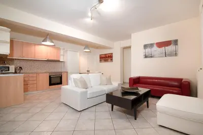 a living room with a white couch and a red chair at SK-George Apartments by the Sea and Airport in Porto Rafti